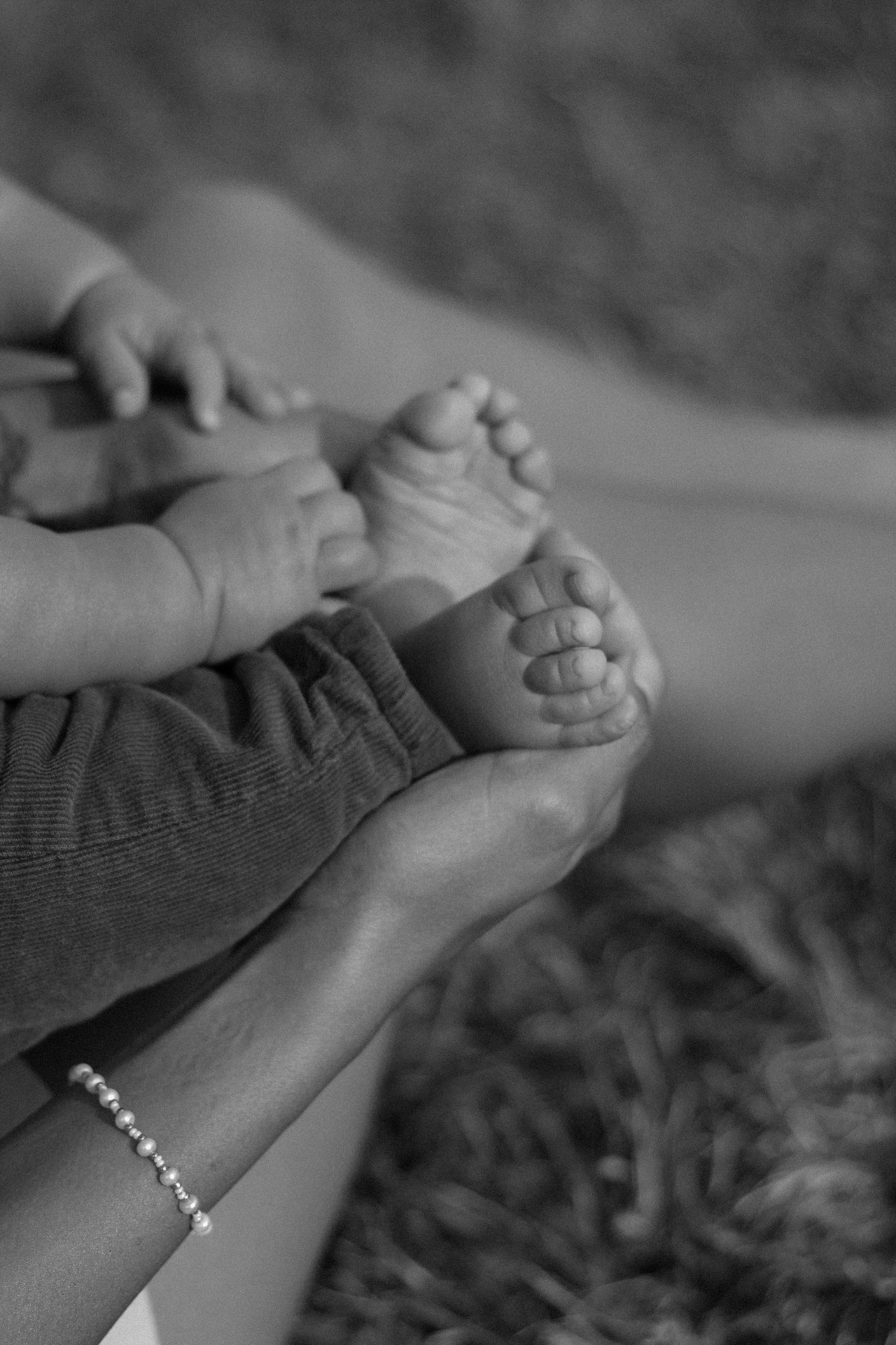 Black and white close-up of baby feet held in hands