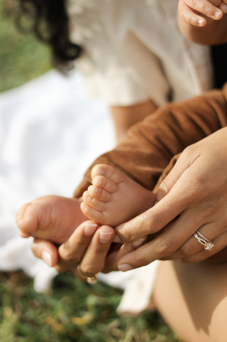 Close-up of baby feet cradled in parents' hands
