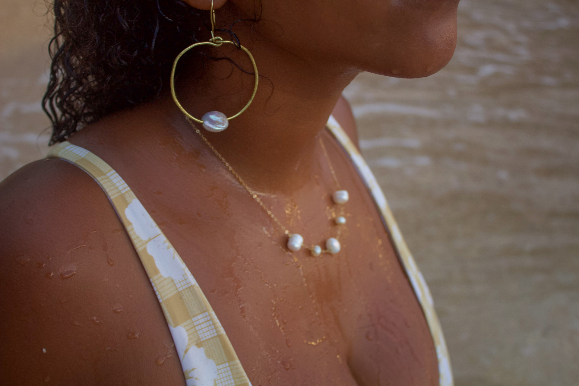 Close-up of pearl earring and layered pearl necklaces on a woman by the shoreline