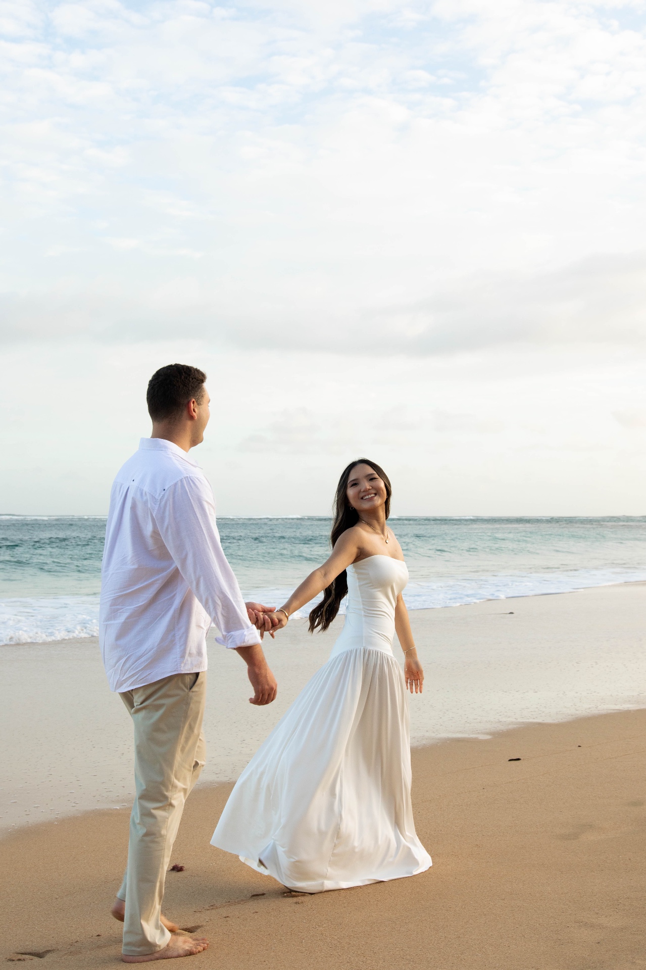 Bride leading groom by the hand along the shoreline at golden hour, Kauaʻi