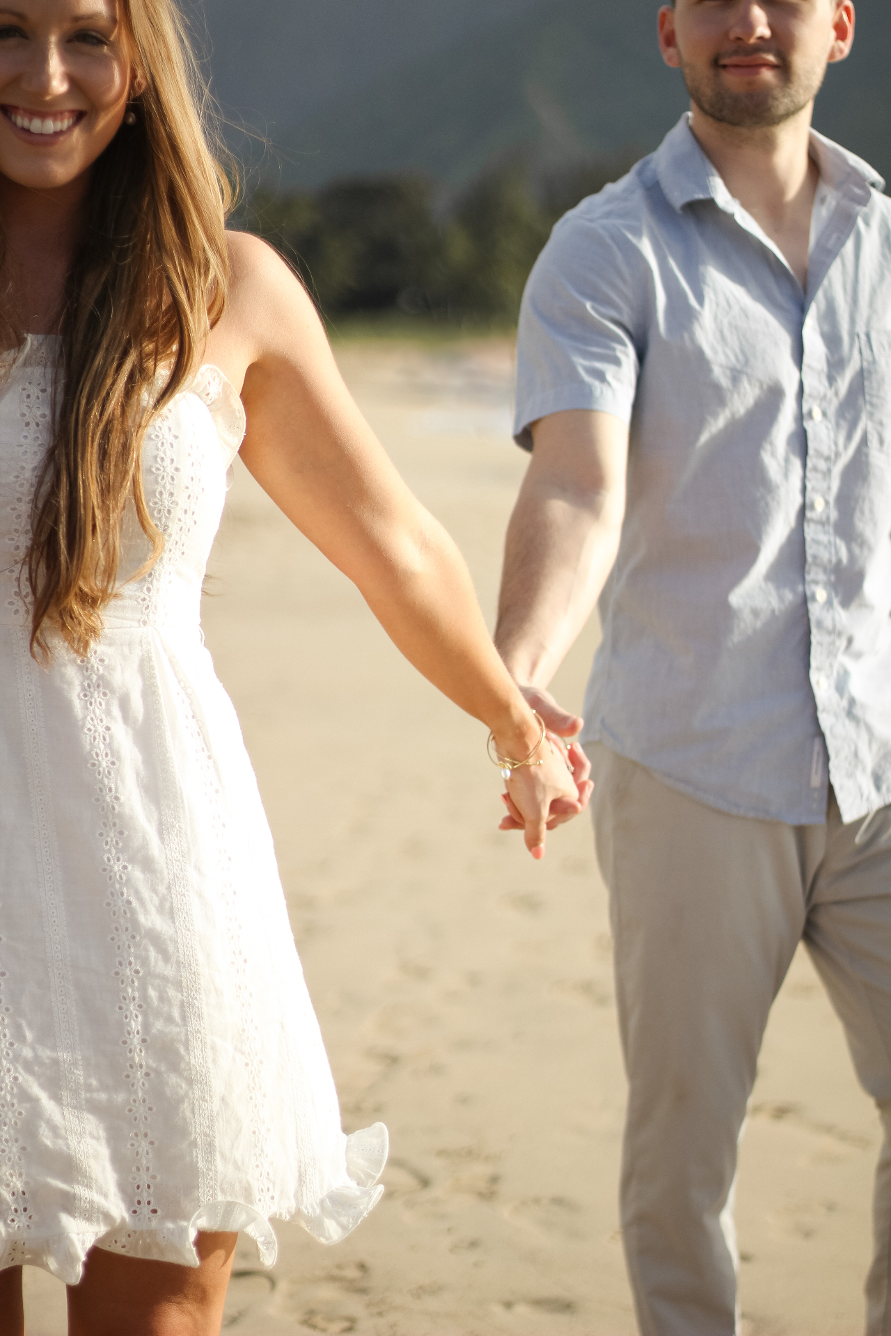 Couple holding hands while walking on the beach in golden light, Kauaʻi