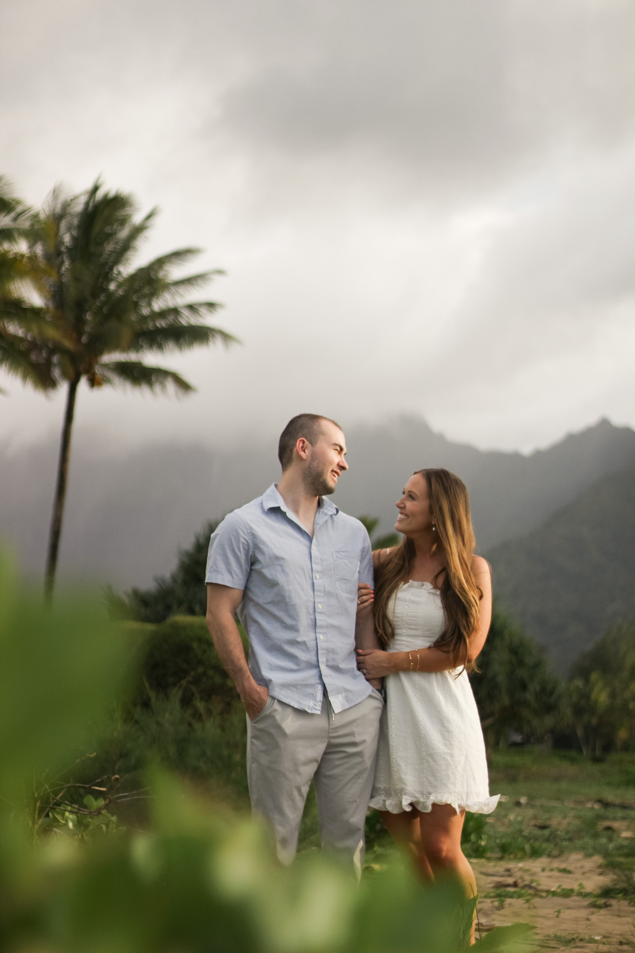 Couple smiling together beneath misty Kauaʻi mountains