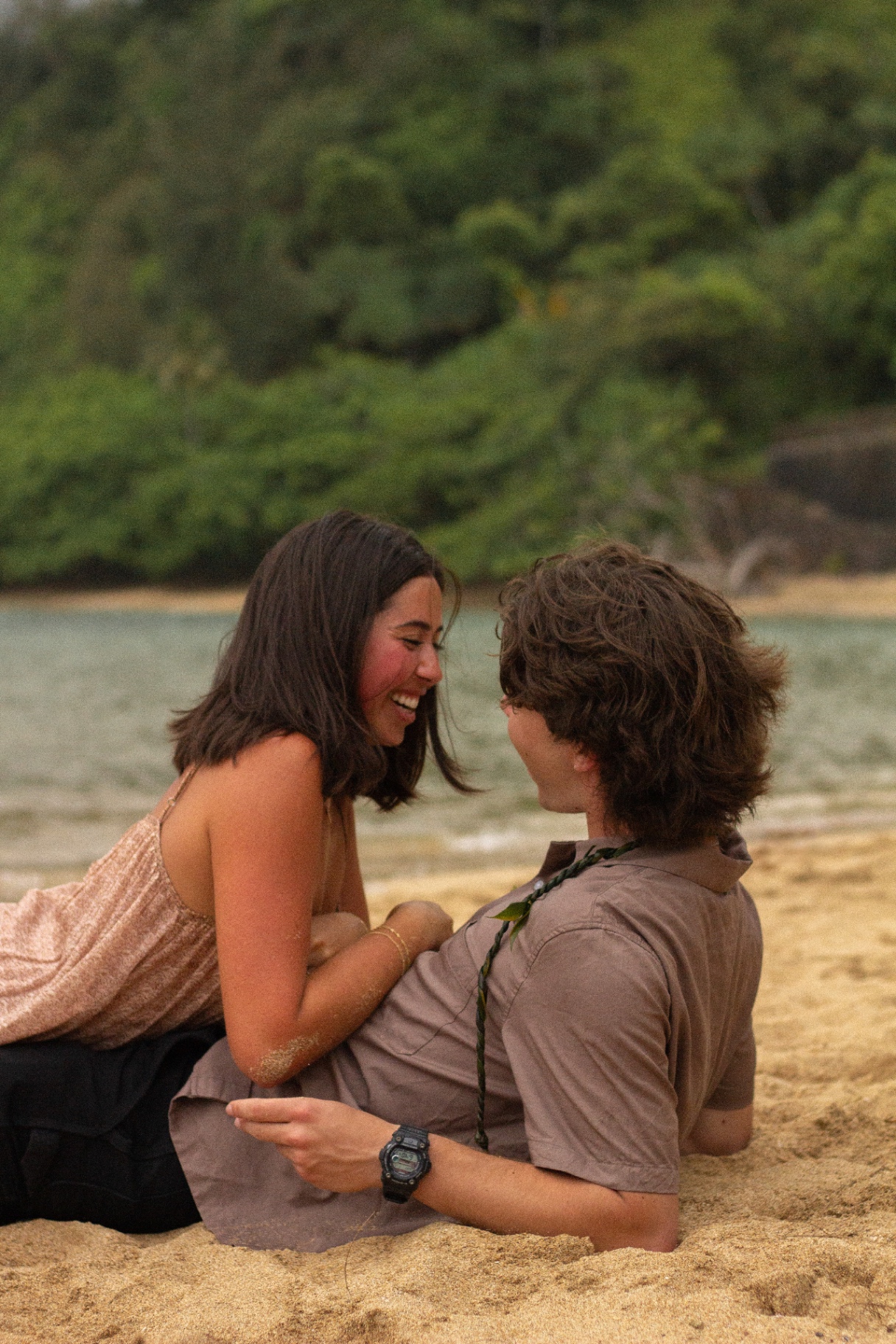 Couple laughing together while lying on the sand, Kauaʻi
