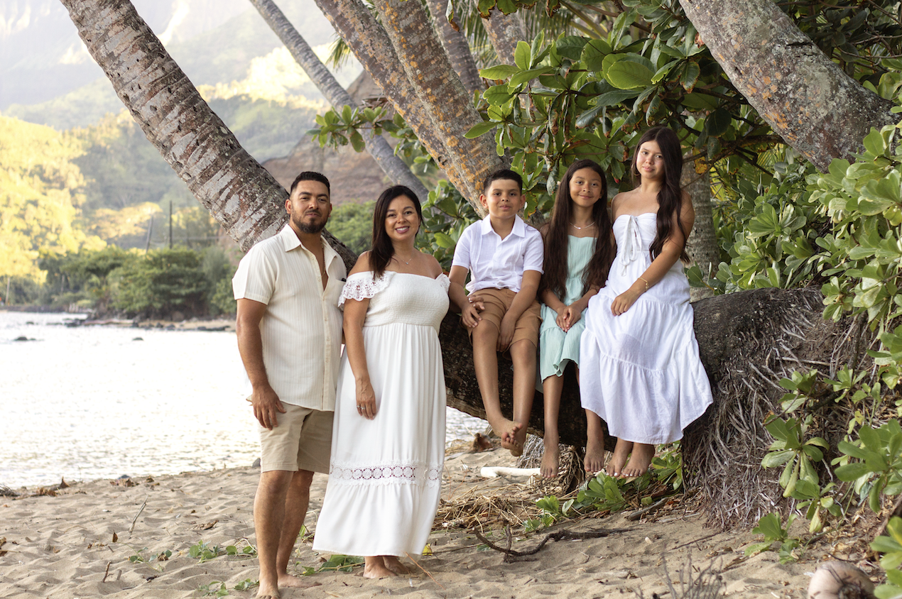 Family of five on the beach beneath palm trees