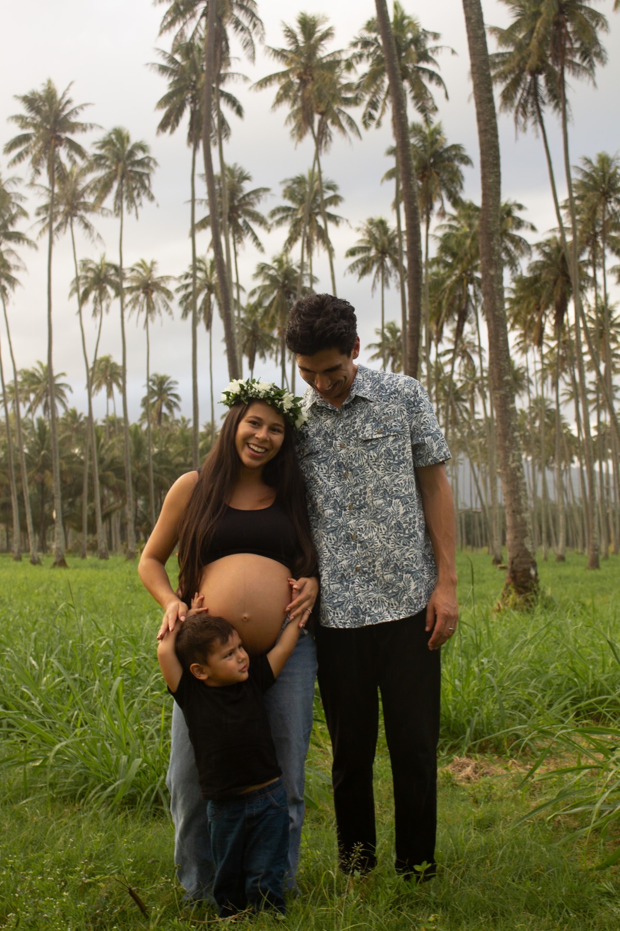 Expecting family standing together in a palm grove