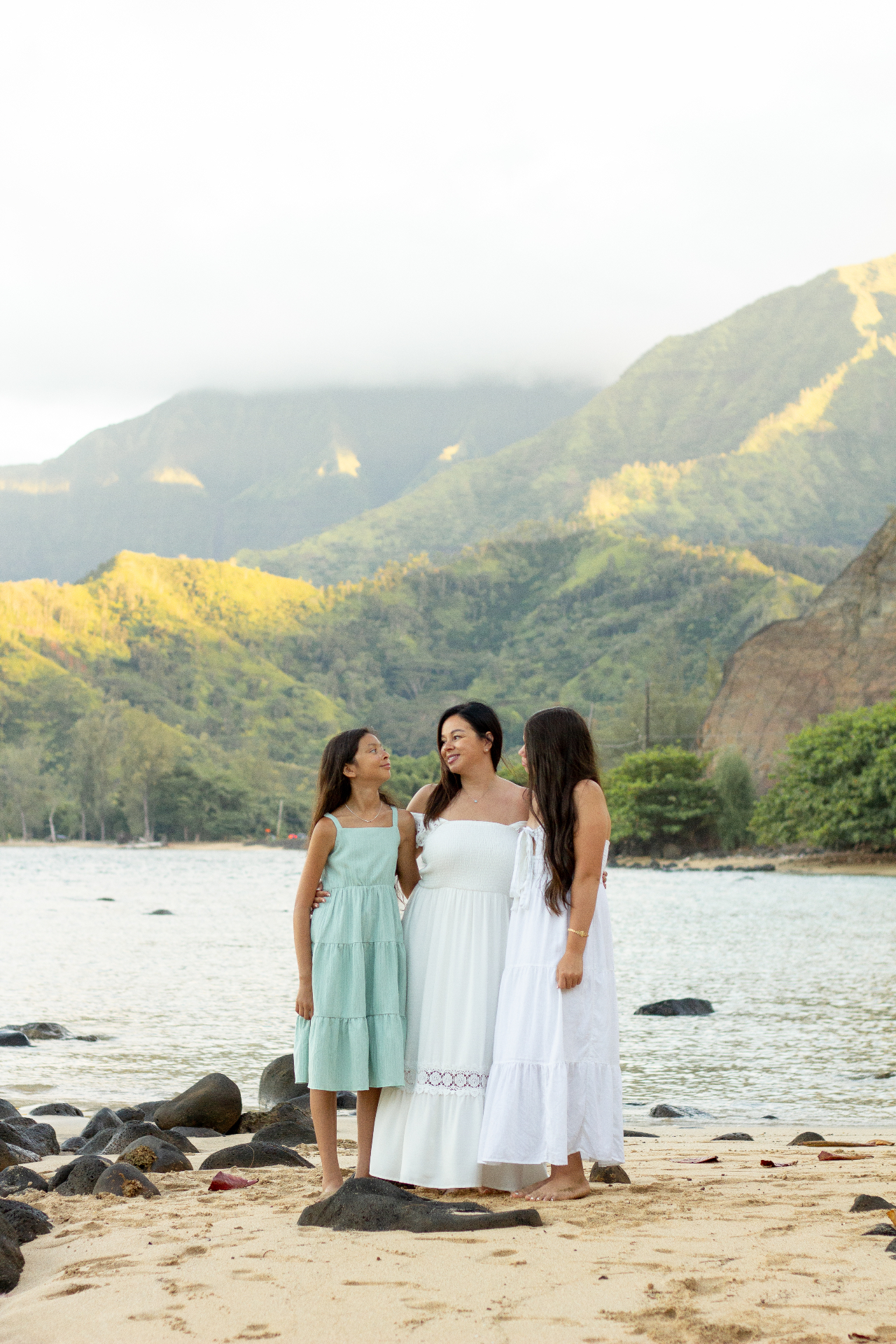Mother and two daughters on the shore with mountain backdrop