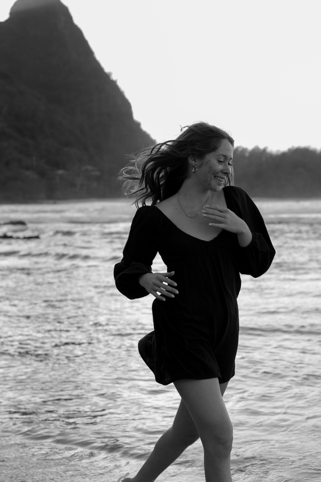 Black and white portrait running along the shoreline with mountain backdrop, Kauaʻi