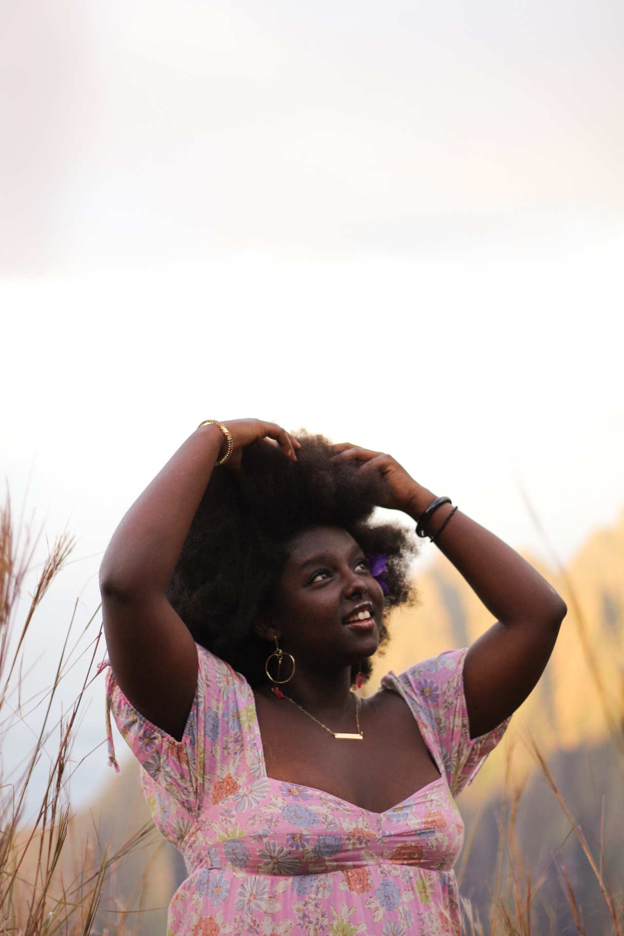 Smiling portrait in floral dress among tall grasses at golden hour, Kauaʻi
