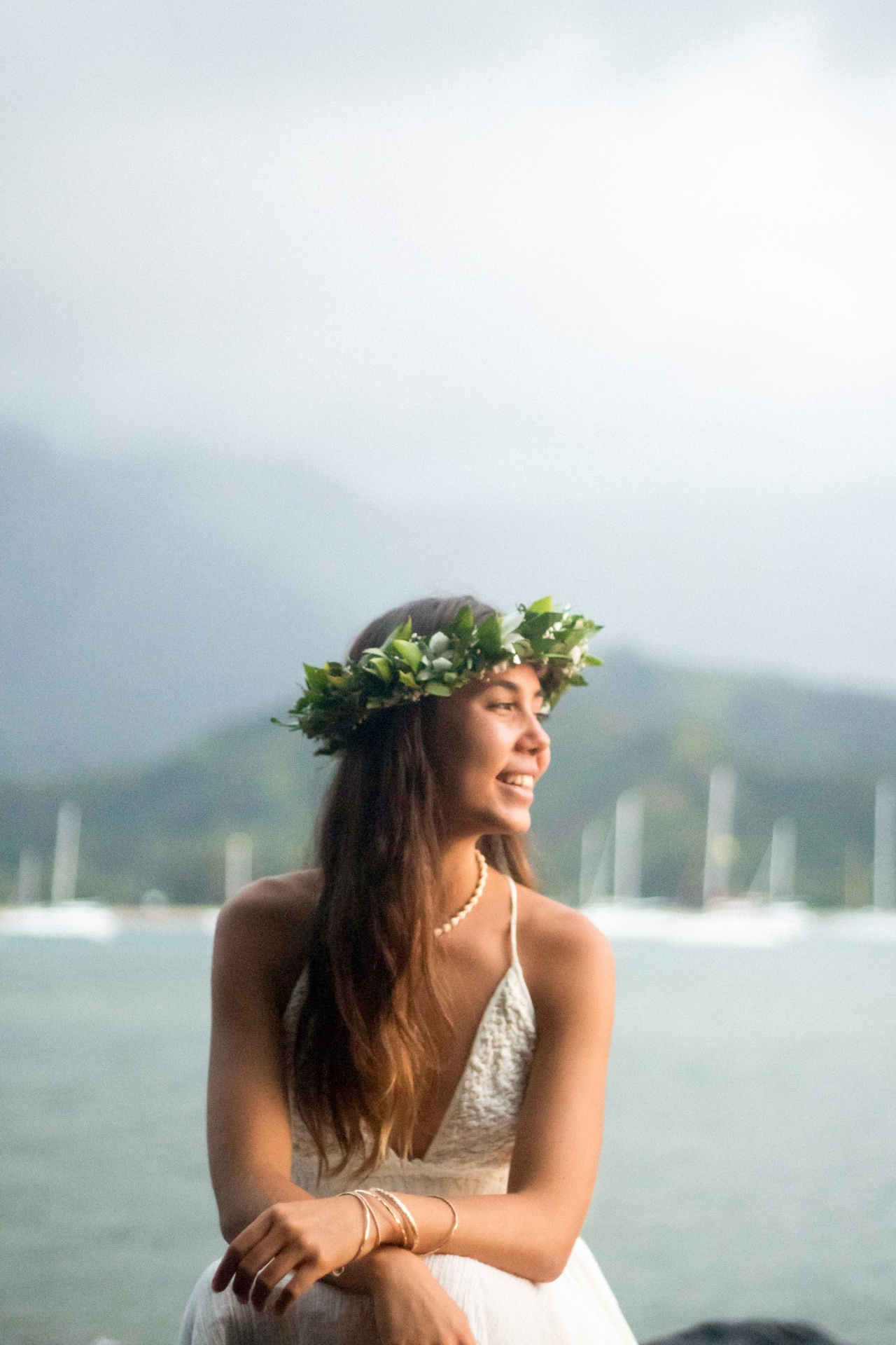 Portrait wearing a green haku lei with Hanalei Bay behind, Kauaʻi