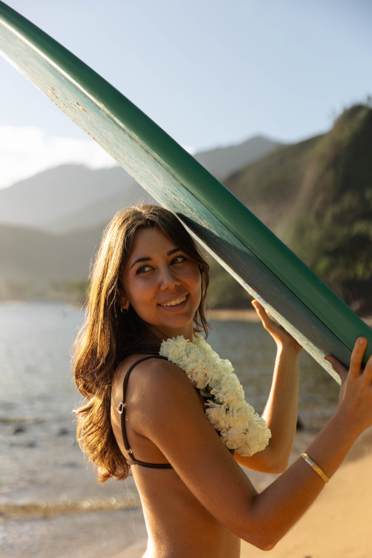 Portrait holding a vintage green surfboard with white lei at golden hour, Kauaʻi